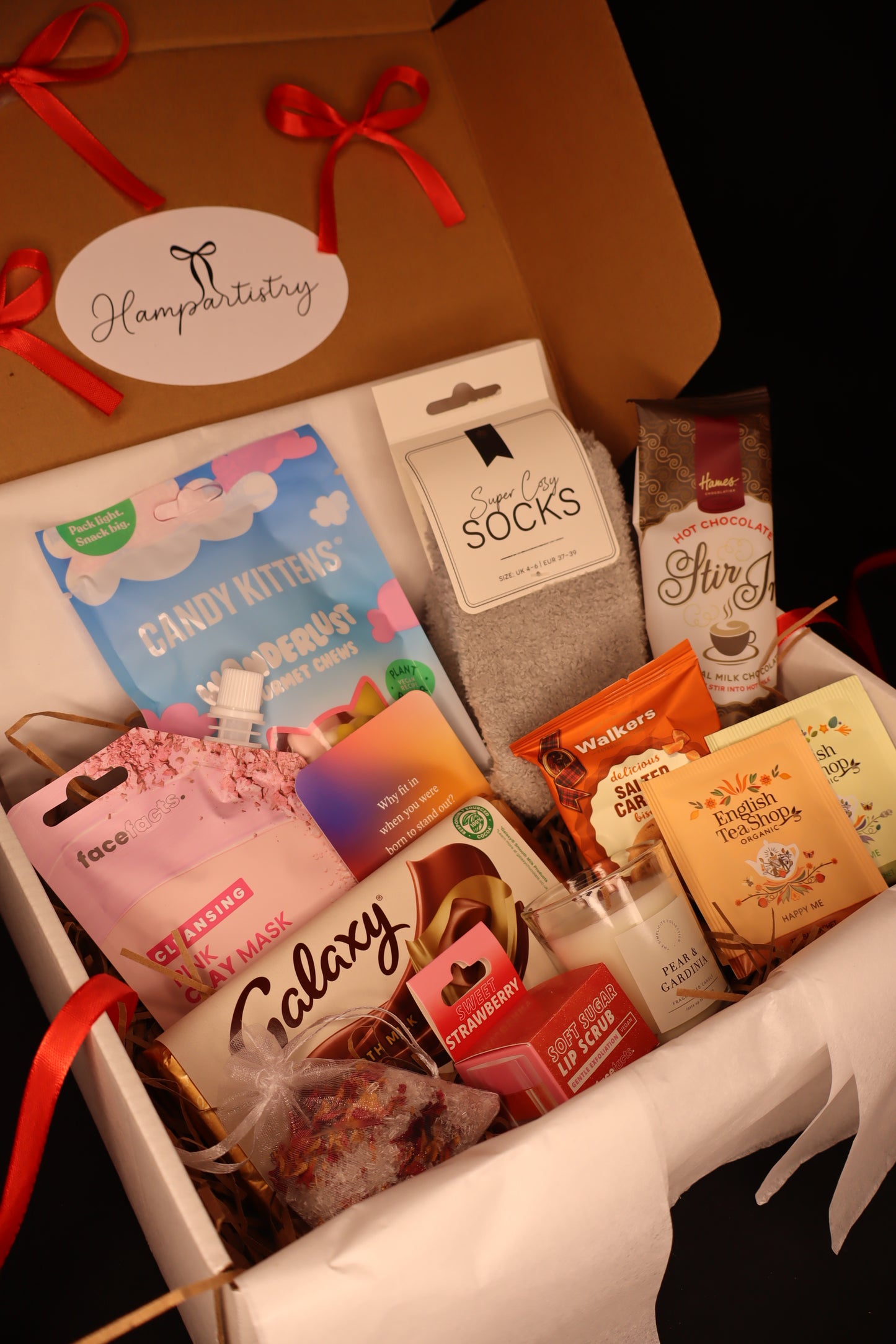 Assorted small packages including candy, socks, and other items in a box with a visible brand label.