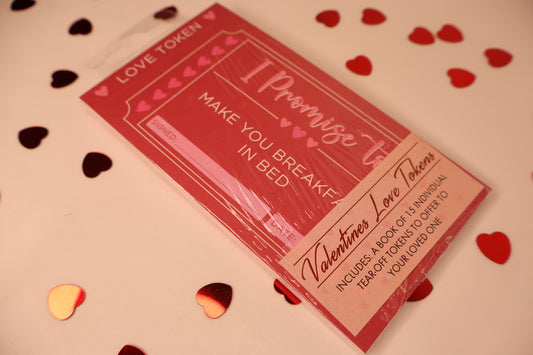 Valentine's Day-themed love token book with heart confetti on a light background