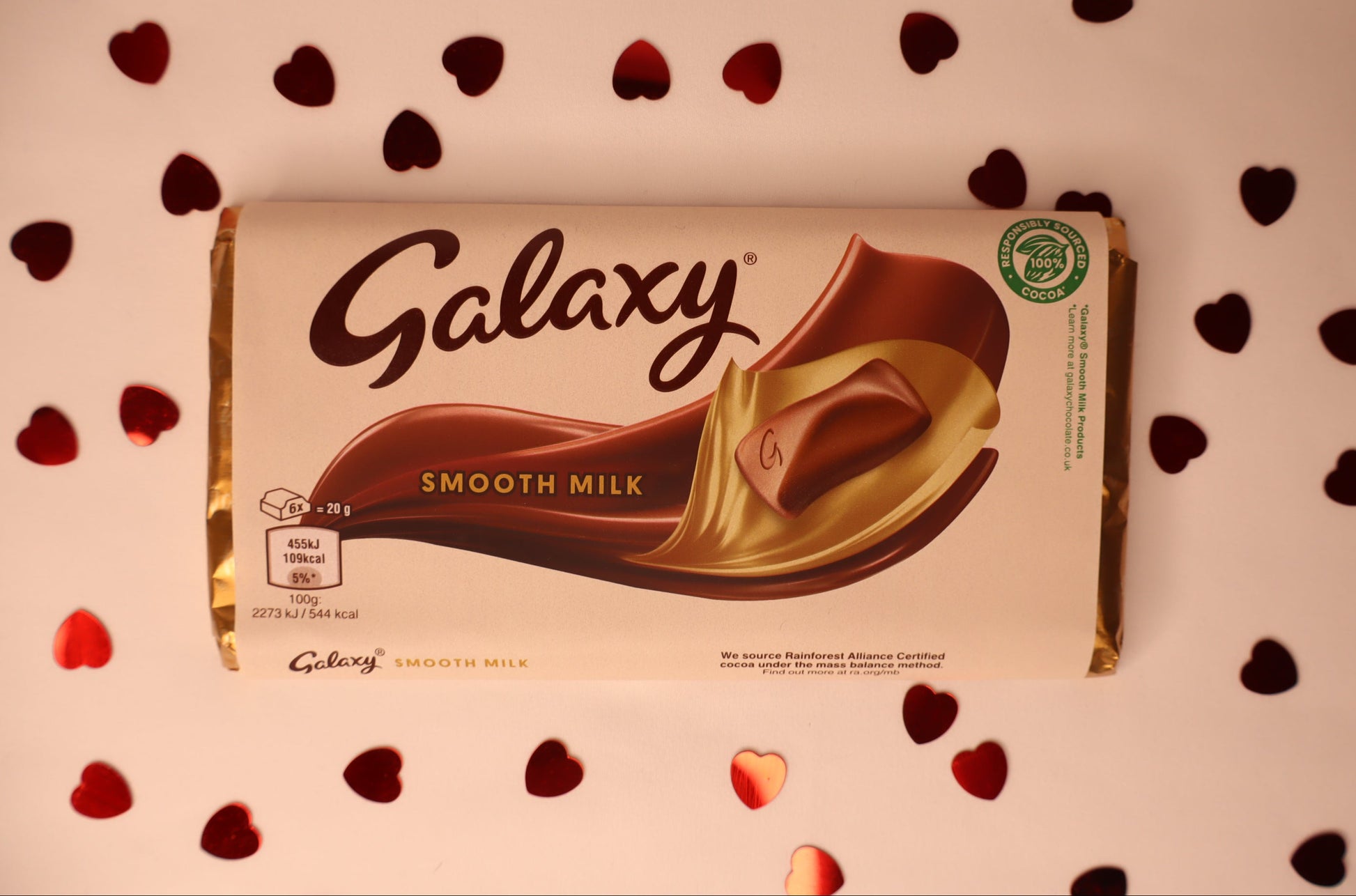 Galaxy Smooth Milk chocolate bar packaging on a decorative background with heart shapes.