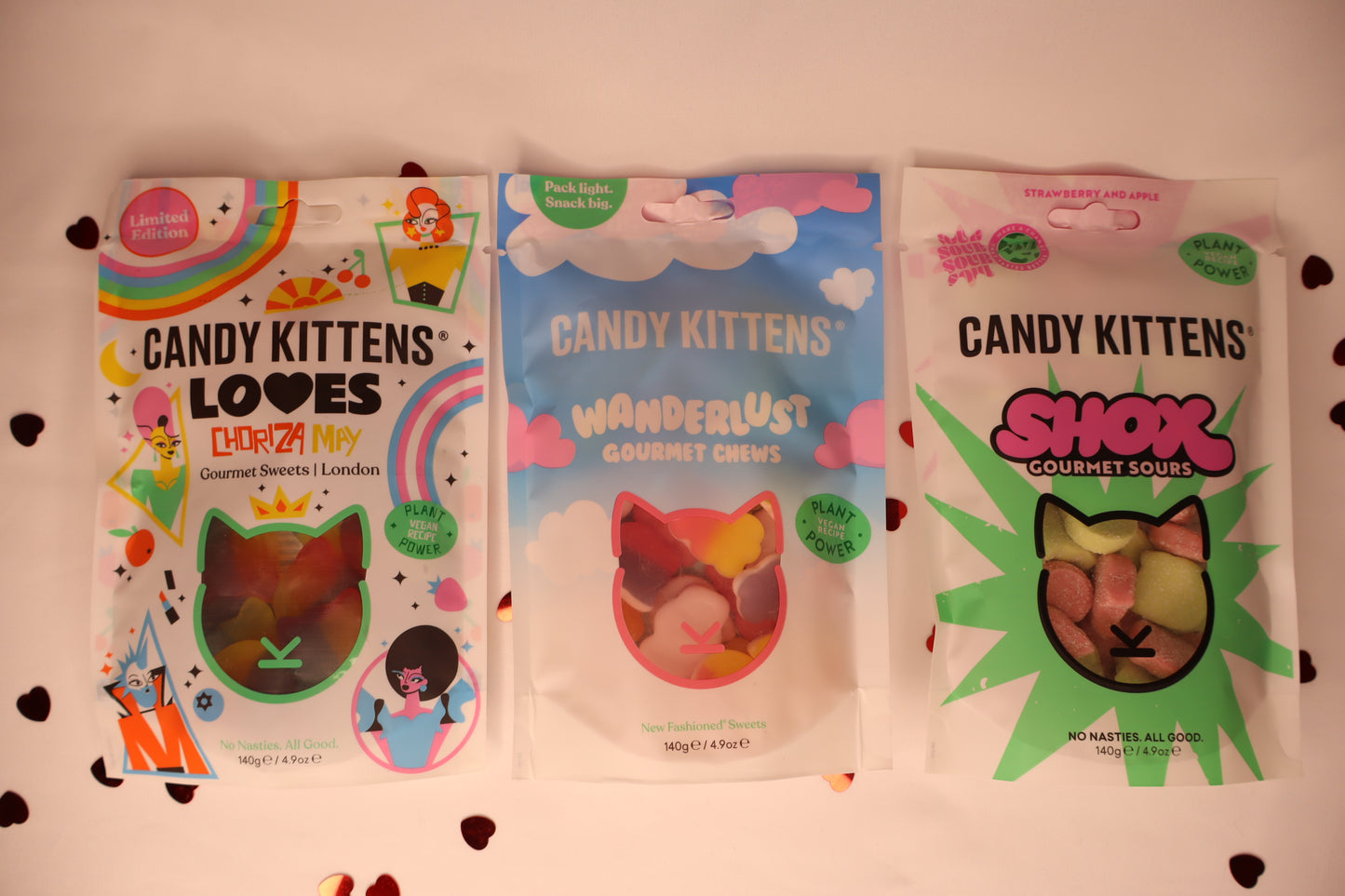 Three packages of Candy Kittens treats on a white background with heart confetti.