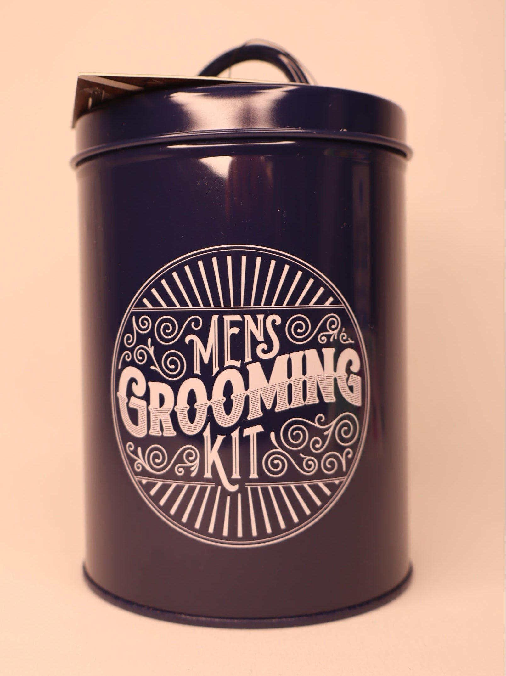 Navy blue tin with 'Men's Grooming Kit' text on a white background